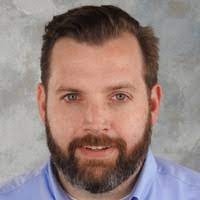 Professional man represents ITSM efficiency in SysAid's Service Desk solutions against a textured gray backdrop. - SysAid