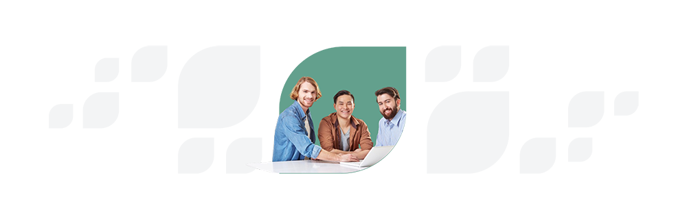Three business professionals, one woman and two men, smiling and discussing over documents at a meeting table.