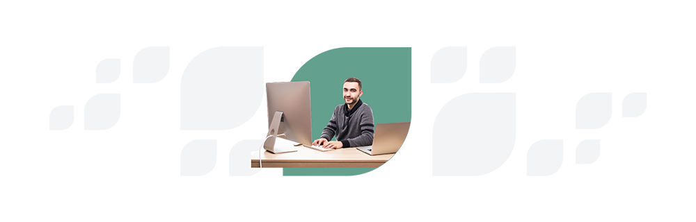 Man in a striped sweater sits at a desk with a computer and notebook, looking at the camera against a split white and teal background.