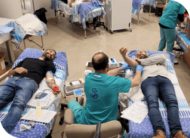 Two men donate blood in a clinic, illustrating SysAid’s Help Desk support for smooth operations in any environment. - SysAid