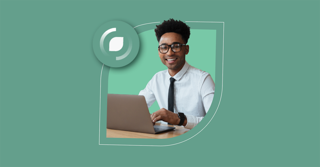 A smiling man in glasses and a tie works on a laptop, representing streamlined ITSM solutions with SysAid's Service Desk tools. - SysAid