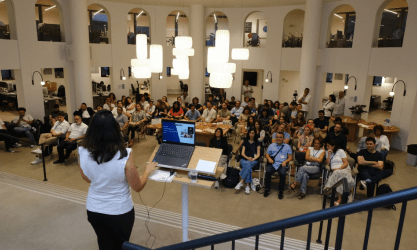 A woman presents ITSM best practices at a SysAid Service Desk event in a modern, collaborative office space. - SysAid